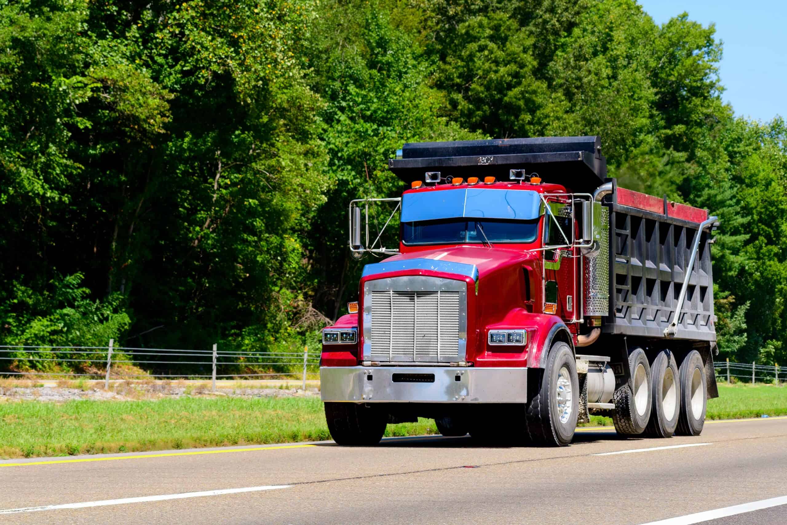 Commercial Truck Insurance Georgia Red dump truck driving on highway in Georgia with green trees.